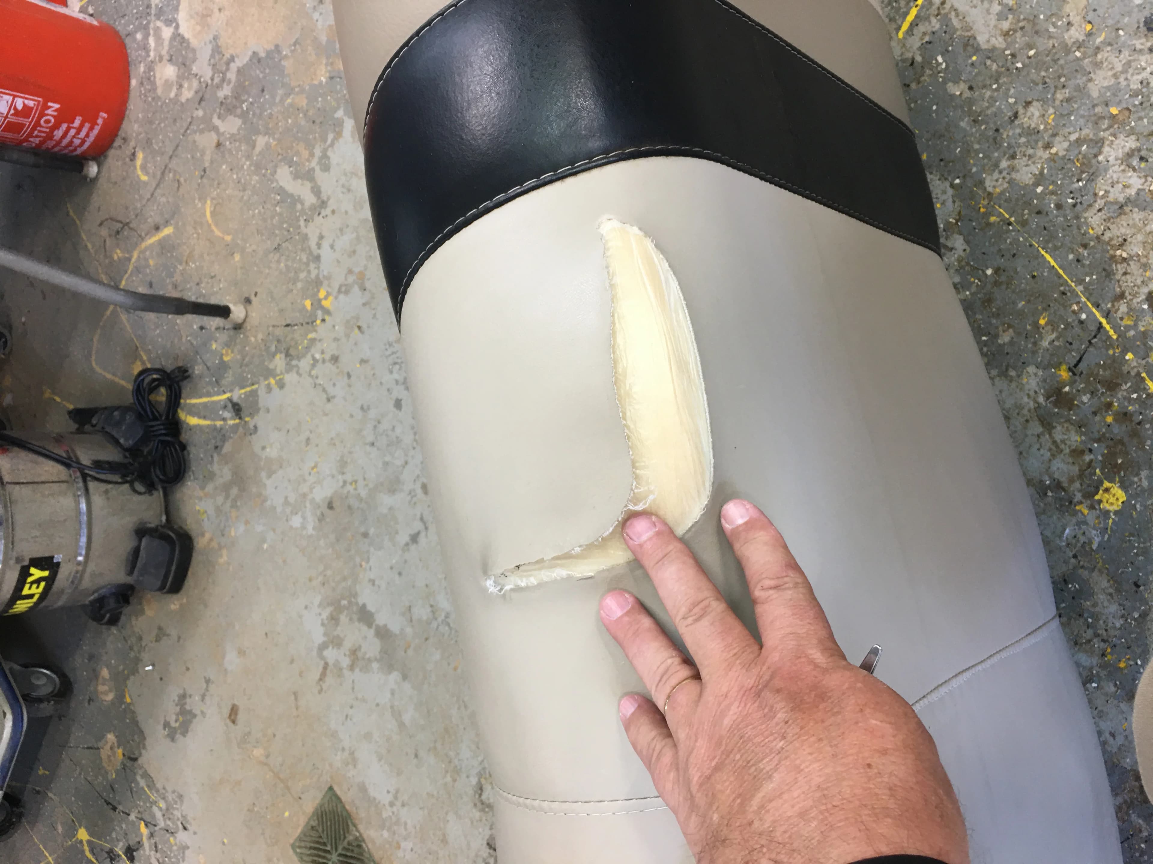 Boat seat with ripped vinyl and foam exposed before repair