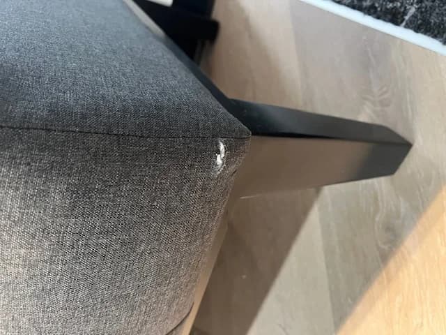 Gray chair showing corner tear damage before repair